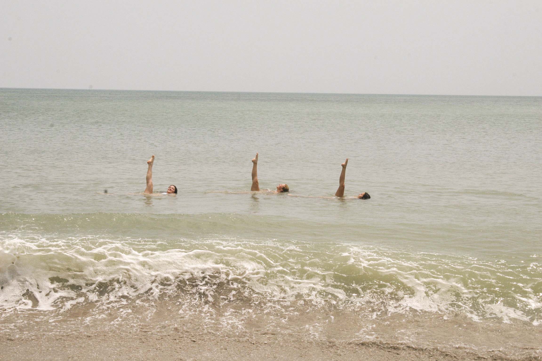 Olivia Heinze and her team members perform practice synchronized swimming at the beach.