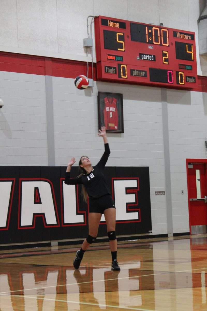 Varsity volleyball player serves the ball against Del Valle. 