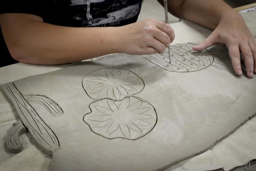 Senior Sami Jo Oates creates cacti and wildflowers for the mosaic mural. 